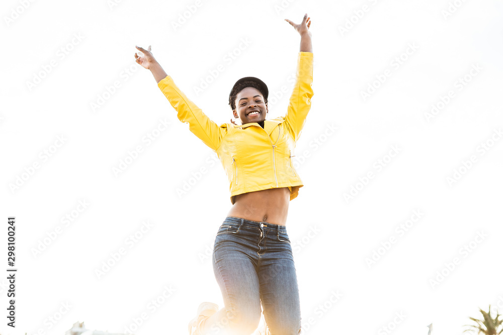 Low angle of happy African American woman in stylish bright jacket ...