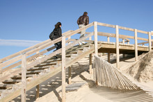 Couple In Winter Wooden Path Stairs Boards Through The Dunes To The Beach Of Lacanau Sea France