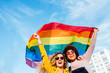 © karrastock - Two women friends hanging out in the city waving LGBT with pride flag