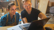 © Gorodenkoff - Couple of Artists Sitting in their Studio Use Laptop Computer, Working on a Project, Talking and Smiling. Painter and Her Partner Doing Research. Authentic Workshop with Oil Paintings and Tools