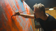 © Gorodenkoff - Portrait of Artist Working on Abstract Painting, Uses Paint Brush To Create Daringly Emotional Modern Picture. Dark Creative Studio Large Canvas Stands on Easel Illuminated. Side View Close-up Shot