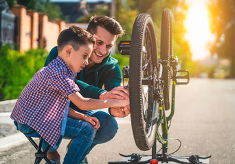 The father and son repair the bicycle together