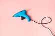 © Yaroslav Danylchenko/Stocksy - New blue glue gun for handcraft working on a color of the year 2019 Living Coral pantone background, copy space.