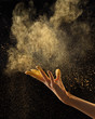 © Yaroslav Danylchenko/Stocksy - Flying abstract yellow powder cloud with wooman hand against black background