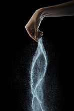 Falling Salt From Woman's Hand On A Black Background, Copy Space.