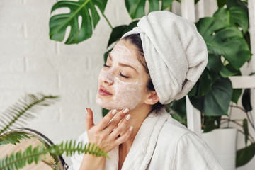 young woman applying face mask at home. natural skin care routine. cleaning face with natural cosmet