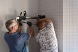 © Milles Studio/Stocksy - Men installing work equipment on wall