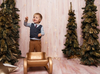 Wall Mural - a boy near the Christmas trees on a sled, Christmas lights, rejoices and smiles, plays. holiday and vacation