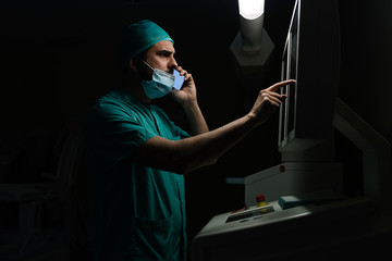 Doctor talking on smartphone while reading medical reports on display screen