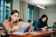 © Maskot - Teenage females studying at desk in classroom