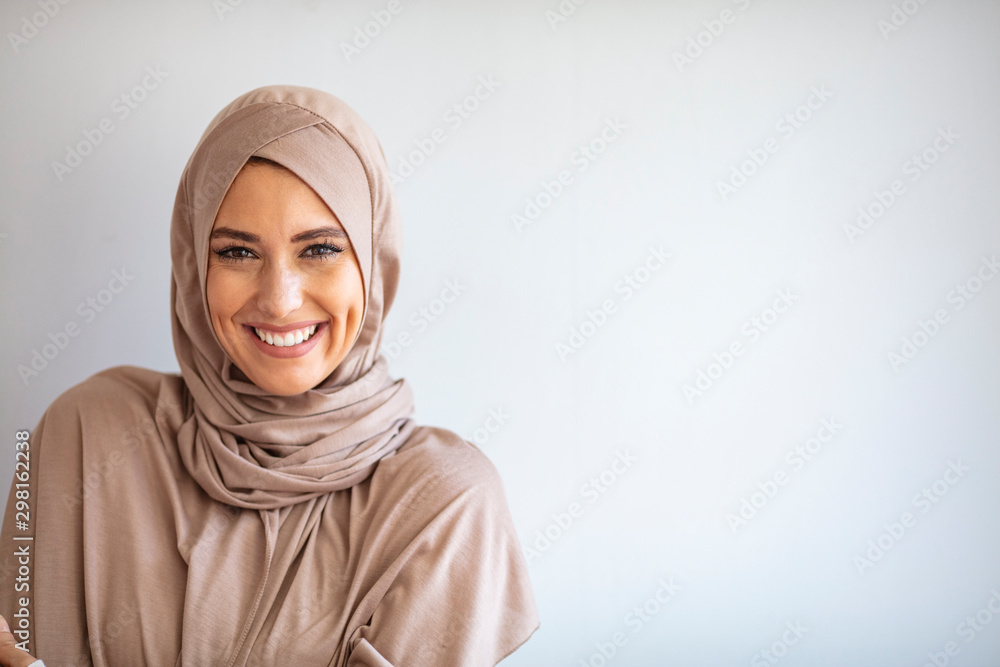 Modern, Stylish and Happy Muslim Woman Wearing a Headscarf. Arab saudi emirates woman covered with beige scarf. "Welcome" Face. One women smile with white background - obrazy, fototapety, plakaty 
