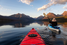 Adventurous Man Kayaking In Lake McDonald During A Sunny Summer Sunset With American Rocky Mountains In The Background. Taken In Glacier National Park, Montana, USA.