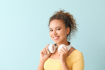 Poster - Beautiful African-American woman with headphones on color background