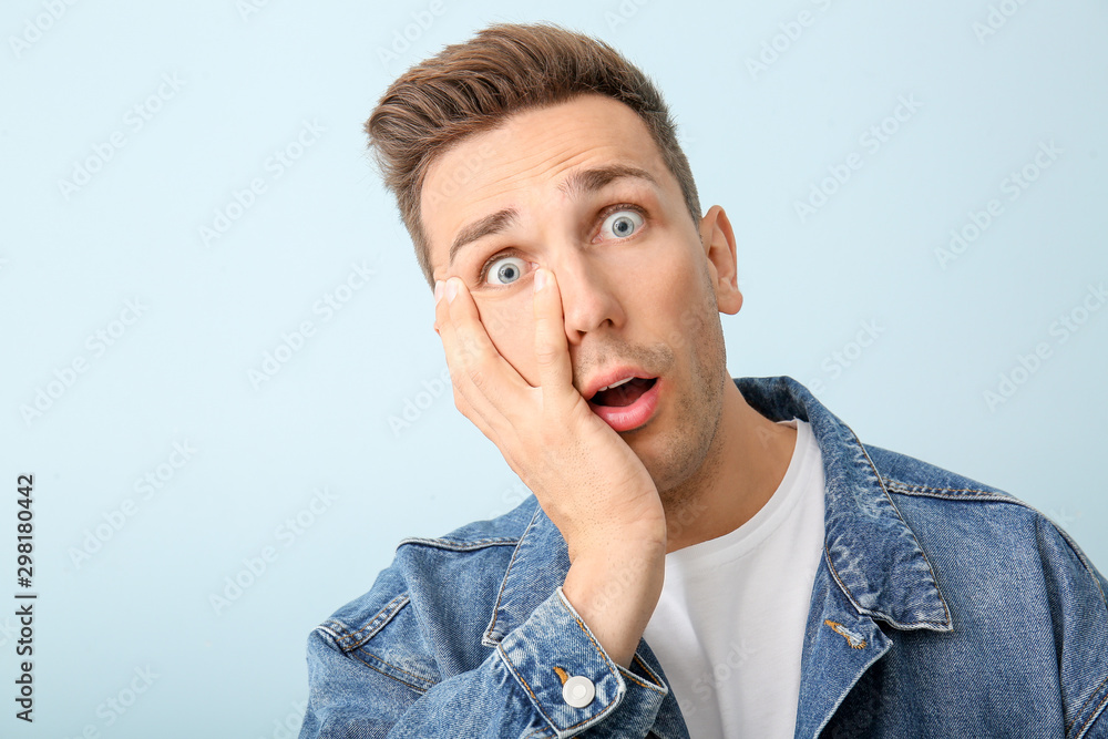 Shocked young man on color background