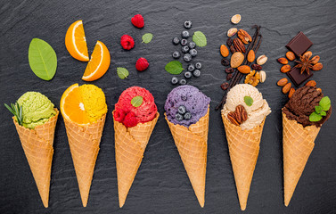 Fototapete - Various of ice cream flavor in cones blueberry ,lime ,pistachio ,almond ,orange ,chocolate ,vanilla and coffee set up on dark stone background . Summer and Sweet menu concept.