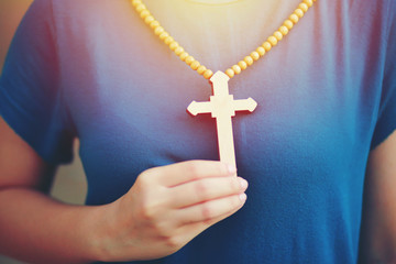 Close-up wooden cross in the hand with focus on the cross blessing from god on sunlight background, hope concept.