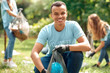 © Viktoriia - Volunteering. Young people volunteers outdoors africa boy close-up picking litter into plastic bag smiling cheerful blurred background