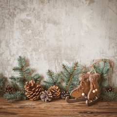 christmas tree branches with cones on a dark wooden board against a gray concrete wall.