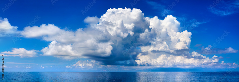 White cumulus clouds in blue sky over sea landscape, big cloud above ...