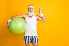 Photo Of Aged Model White Hair Guy Hold Green Fit Ball Showing Okey Symbol Advice Great Trainer Wear Tank-top Striped Shorts Sweatband Isolated Yellow Color Background