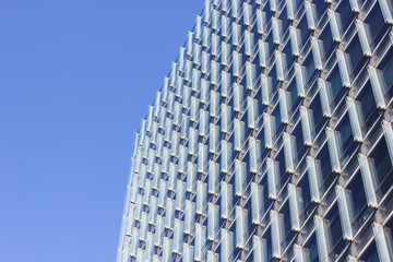 Geometrical lines of glass building wall with sky reflected