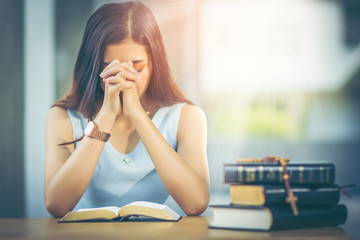 Asian girl with long hair. Read the holy bible and pray for the blessing of Christ. The atmosphere light from above, which represent a symbol of of hope and salvation from the Lord with copy space.