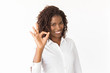 © Mangostar - Happy joyful client making ok gesture. Young African American business woman standing isolated over studio background, showing Okay sign. Agree gesture concept