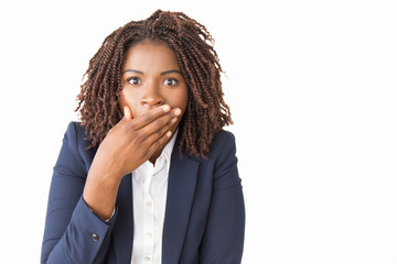 Wall Mural - Shocked scared female employee covering mouth with hand. Young African American business woman with wide eyes staring at camera, posing isolated over white background. Shock concept