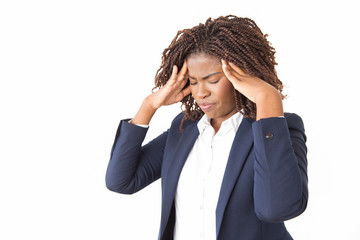 Wall Mural - Stressed unhappy businesswoman suffering from headache. Young black business woman with pain face and closed eyes standing over studio background, holding head and temples. Migraine concept