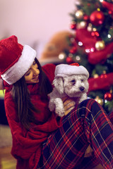  smiling  girl in santa hats embracing cute puppy.Cute dog for Christmas gift.