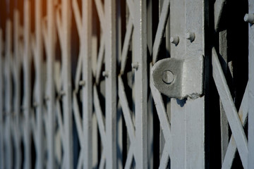 Wall Mural - Side view and close up hasp of the old steel folding door with flare light and blurred background, house security concept