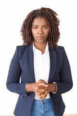 serious female manager posing with clasped hands. young african american business woman standing iso