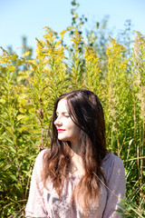 Beautiful brunette woman with red lips on the field in the summer