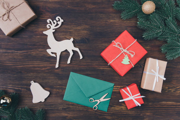 Wall Mural - Merry xmas time. High angle above overhead view photo of beautiful white colorful red and green objects golden shiny balls evergreen fir branches reindeer giftboxes on rustic dark backdrop