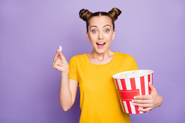 Sticker - Photo of brunette white trendy cheerful millennial watching movie excited about unexpected events in plot holidng bucket of pop corn expressing amazed emotions isolated violet pastel color background