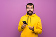 Handsome man with yellow sweatshirt surprised and sending a message