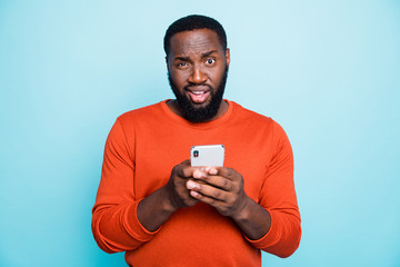 Photo of unsure man mixed-race looking at you with arrogance holding telephone browsing through this to find truthful information isolated vivid color blue background
