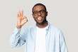 © fizkes - Head shot portrait happy African American man showing ok gesture