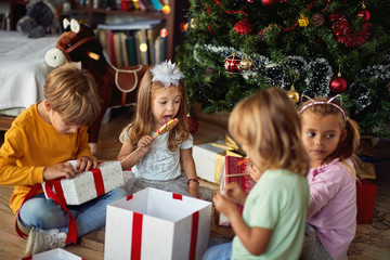 Cute children opening  Christmas gift at home.