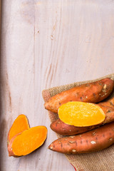 Wall Mural - Raw sweet potatoes on wooden background