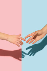 Female and male hands holding on pink and blue background. Concept of human emotions, expession, feelings, relations, ad, love, friendship. Gesturing, meeting, greeting.