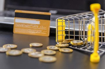 Shopping cart with scattered gold coins and a credit card near the laptop close-up. The concept of shopping online, shopping on credit