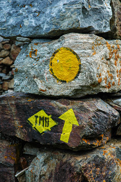 Letters TMB meaning Tour du Mont Blanc and a direction arrrow painted on a rock. A classic multiday hike in the French Alps