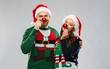 © Syda Productions - people and holidays concept - portrait of happy couple in santa hats making noses of red christmas balls at ugly sweater party