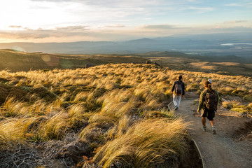 Hikers relaxing on te way of a mountain and enjoying the view of valley at sunset. trekking day