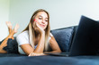 © dianagrytsku - Smiling young woman laying on couch and using laptop at home