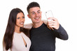 © Ranta Images - Happy young couple smiling while man taking selfie together with