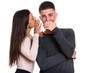 © Ranta Images - Woman whispering secret to man while man looking surprised