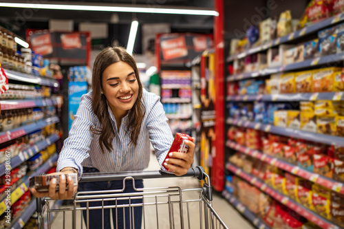 Fotografía Woman with shopping trolley in supermarket aisle