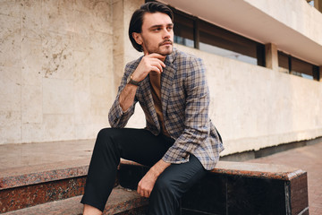 Young attractive man in checkered jacket confidently looking away outdoor